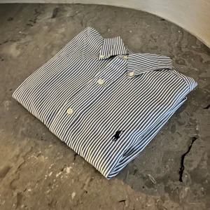 Ralph lauren skjorta - Hej! Säljer nu en stilren Ralph lauren skjorta som är randig, toppen skick inga defekter, arm längd är 62 cm och bröstkorg/midja är 53cm, skriv om ni har några funderingar och pris kan diskuteras😁