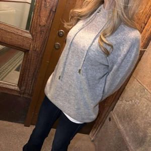 Merino-Ull Grå hoodie  - Säljer en stilren grå hoodie med justerbar dragsko i huvan. Perfekt för en avslappnad look. Den har en normal passform och är tillverkad i ett mjukt material.