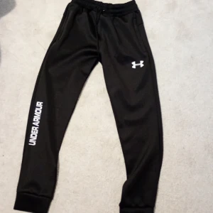 Svarta mjukisbyxor från Under Armour - Snygga svarta mjukisbyxor från Under Armour med elastisk midja och logga på benet. Perfekta för en avslappnad stil eller träning. De har en bekväm passform och är gjorda i ett mjukt material. Och en bekväm kofta som är beige och bekväm. Storlek S men passar XS den är helt ny och inte andvänd. Pris kan diskuteras 