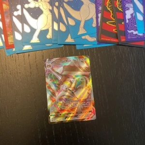 Pokémonkort: Melmetal VMAX, Mewtwo V, Egg Incubator, Mew VMAX - Säljer en samling Pokémonkort inklusive Melmetal VMAX, Mewtwo V, Egg Incubator och Mew VMAX. Korten har en glittrande finish och är perfekta för samlare eller spelare. Varje kort har unika egenskaper och design som gör dem speciella. Perfekt tillägg till din Pokémon-kortsamling!