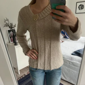 Beige stickad tröja med knappdetalj - Säljer en beige stickad tröja med en unik knappdetalj vid halsen. Den är i storlek M men passar även S skulle jag säga.💕 Hör av er vid frågor!