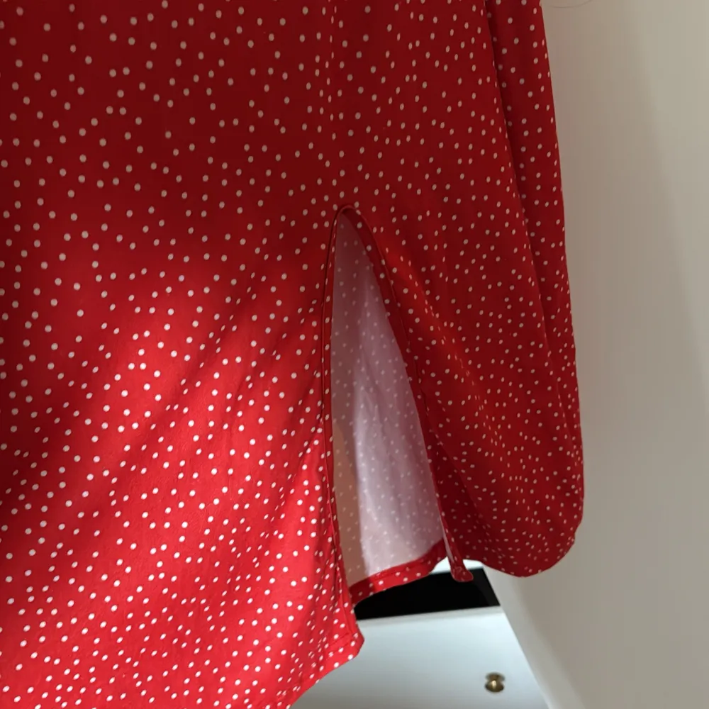 Charmig röd klänning med vita prickar från SHEIN. Den har en söt knytning framtill och en slits. Klänningen är offshoulder med korta puffärmar. Mekot.