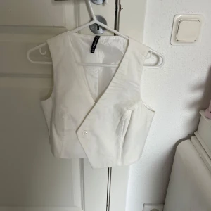 Vit väst från Sister - Snygg vit väst från Sister i storlek XS. Västen har en stilren design med knappar framtill och en klassisk passform. Perfekt för att lägga till en touch av elegans till din outfit.