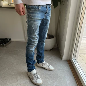 Blå jeans från Replay - Snygga blå jeans från Replay med en klassisk femficksdesign och knappgylf. De har en lätt tvättad look och broderad detalj på bakfickan. Perfekta för en avslappnad stil. 9/10