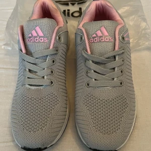  Adidas performance - Damsneakers - Strl 39 - Ett par bekväma Adidas performance damsneakers i en stilren grå och rosa färgkombination med snörningen. Perfekt för vardagsbruk eller lättare träning.  Ovandel design är mycket lätt och mjuk, det stickade nätet är mycket andningsbart.