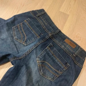 Blå jeans från Multiblu - Säljer ett par blå jeans från Multiblu med klassisk femficksdesign och knappgylf. Lågmidjade, utsvänga. Jeansen har en rak passform och är i storlek W34 L30. Perfekta för en avslappnad stil.