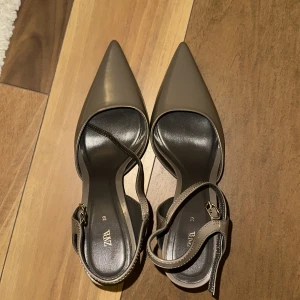 Spetsiga Klackar kittenheels Zara - Snygga beige/brun klackar från Zara med spetsig tå och elegant klack. Skorna har en smidig rem med spänne runt ankeln för extra stil och komfort. Perfekta för att lyfta vilken outfit som helst. Helt nya 