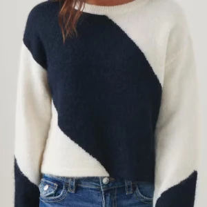 Svartvit stickad tröja - Snygg och trendig svartvit stickad tröja med ett diagonalt mönster. Tröjan har långa ärmar och en croppad passform som ger en modern look. Perfekt för kyligare dagar.