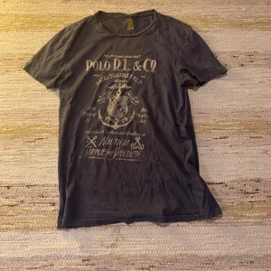Mörkblå t-shirt från Polo Ralph Lauren - Säljer en mörkblå t-shirt från Polo Ralph Lauren med  tryck på framsidan. Skick 8/10 och inga defekter. Den är riktigt sval och perfekt för våren och sommaren. Pris kan diskuteras! 