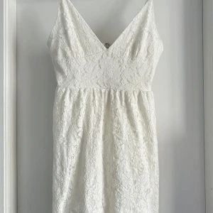 Vit spetsklänning från NLY Eve - Säljer en elegant vit spetsklänning från NLY Eve. Klänningen har en v-ringad design och är ärmlös med justerbara axelband. Perfekt till studenten eller sommarens festligheter 💫. Oanvänd