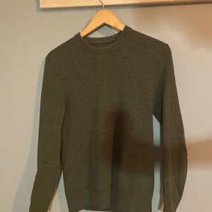 Olivgrön stickad tröja - Säljer en stilren olivgrön stickad tröja med rund halsringning. Tröjan har långa ärmar och en enkel design som passar perfekt för kyligare dagar. Perfekt för lager-på-lager-stil. Absolut älskar denna men måste skiljas på grund av att den har blivit för liten 😞. Några hål men inget jag märker kanske är för att jag inte har några glasögon på men det är merino så det finns nästan alltid hål i. Pris kan diskuteras eftersom att det inte finns någon tag. Fråga mig vad som helst utom om vetenskaplighet