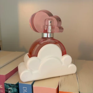 Ariana Grande Cloud Pink Parfym - Superfin parfym från Ariana Grande med en rosa flaska formad som ett moln och vit molnbas. Flaskan har en unik och lekfull design som verkligen sticker ut på hyllan. Perfekt för dig som gillar söta och fräscha dofter. Endast testad 