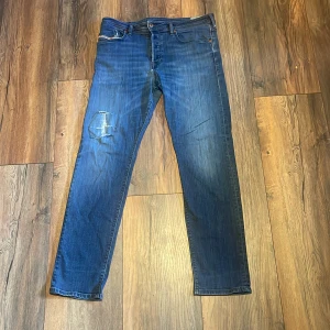 diesel jeans - Dem är ungefär 1m långa och 43cm i midjan.Säljer ett par klassiska blå jeans från Diesel med straight fit. Jeansen har fem fickor, snygga slitningar och en liten Diesel Industry-logga på myntfickan. Perfekta för dig som gillar en tidlös look med lite edge.