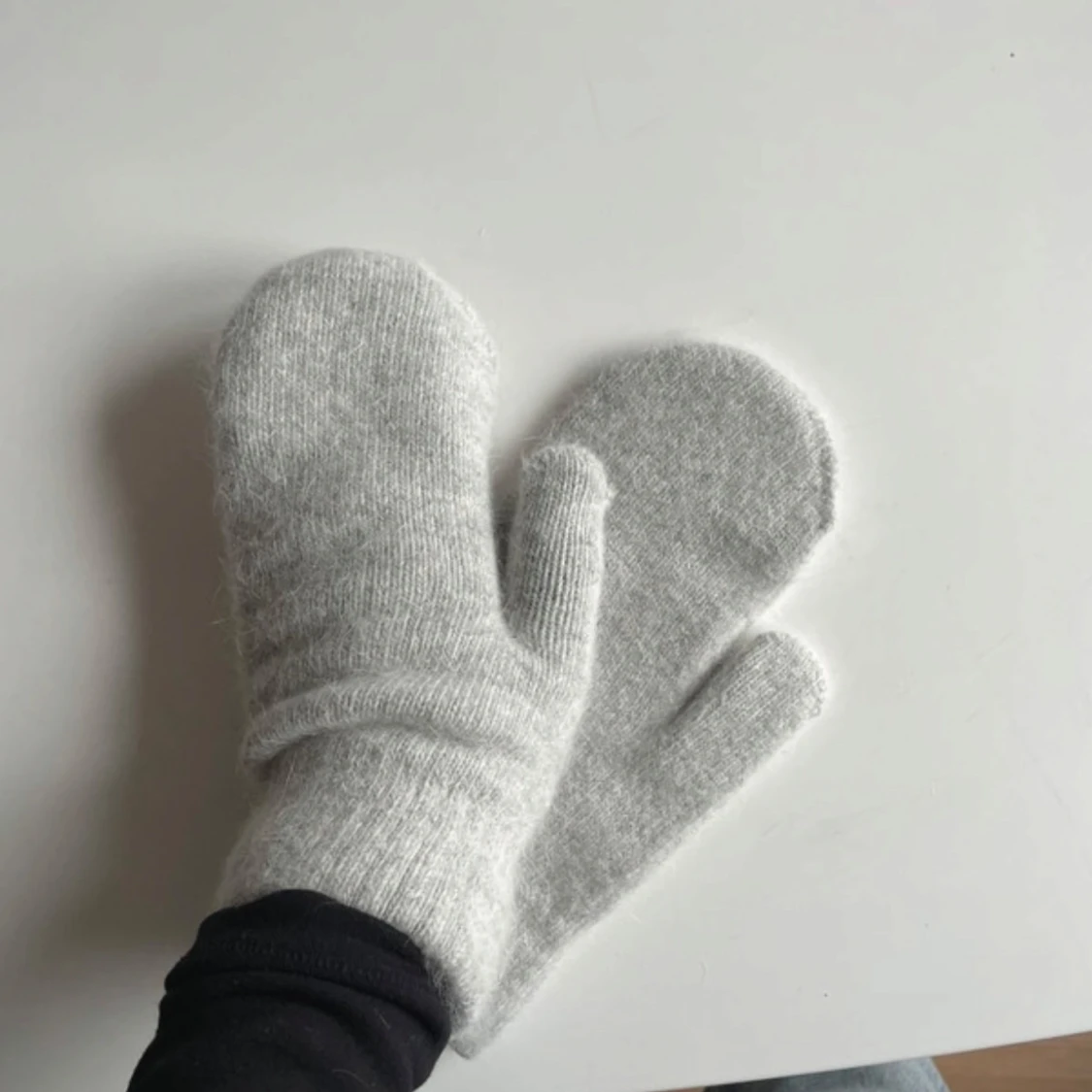Ljusgrå stickade tumvantar