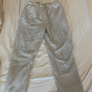 Grå mjukisbyxor med snörning - Grå mjukisbyxor med elastisk midja och snörning. Byxorna har resår vid bensluten och är tillverkade i mjukt bomullsmaterial. Är nopprig på insidan av låren, från Gina tricot i storlek S