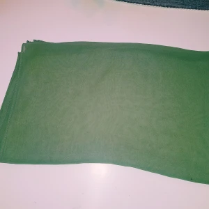Grön sjal i tunt tyg - Enkel och stilren grön halsduk i tunt, mjukt tyg. Perfekt att slänga över axlarna för en snygg touch till outfiten. Rektangulär form och enfärgad design gör den lätt att matcha med det mesta.  Liten tråddragning (inga hål) & obehandlad fläck