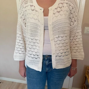 Vit stickad kofta från Indiska XL - Säljer en vit stickad kofta från Indiska i storlek XL. Koftan har ett luftigt, virkat mönster, knappar framtill och trekvartsärmar. Perfekt att slänga över ett linne för en chill och fräsch look. Superfin till både jeans och kjol! Koftan är endast provad!