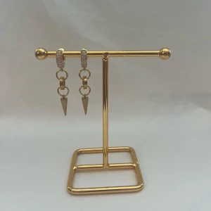 Guldiga örhängen med kedjor och spikes - Snygga örhängen i guldton med små glittriga stenar på ringen och coola kedjor som avslutas med spetsiga spikes. Perfekta för dig som vill sticka ut med en edgy vibe. Passar till både street och trendiga looks.