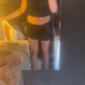 Svart ribbad minikjol - Säljer en svart ribbad minikjol med tight passform. Kjolen är stretchig och sitter snyggt i midjan. Perfekt för dig som gillar en enkel men trendig look. Materialet är mjukt och följsamt, vilket gör den superbekväm att bära.