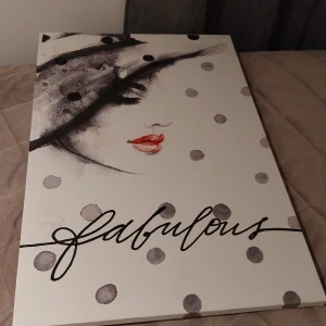 Fabulous - En stilren tavla  med ett konstnärligt omslag i svartvitt och röda läppar, prydd med ordet 'fabulous' i snygg handstil. Perfekt för dig som gillar mode och konst!