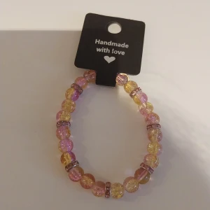 Handgjort pärlarmband rosa/gult - Superfint handgjort armband med glittriga pärlor i rosa och gult, varvat med små glittriga mellanringar. Perfekt accessoar för att liva upp din outfit med lite färg och sparkle!