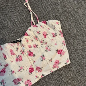 Blommig croppad linnetopp från Zara - Supersöt  topp vit bomull med rosa blommigt mönster, broderade detaljer och lätt rynk vid bysten.