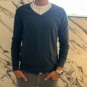 Mörkblå v-ringad tröja Hilfiger Denim - Mörkblå v-ringad tröja från Hilfiger Denim i storlek XL som har krympt till L. Tröjan har lång ärm, liten broderad logga på bröstet och är tillverkad i mjukt material som känns skönt mot huden. Perfekt för dig som gillar en clean och klassisk stil.