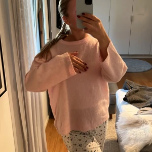 Ljusrosa stickad tröja från 157 - Supermjuk och oversized ljusrosa stickad tröja från 157. Tröjan har rund halsringning, långa ärmar och en relaxed fit som ger en chill vibe. Perfekt att slänga på sig när du vill vara både bekväm och snygg.