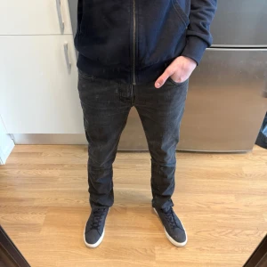 Nudie Slim Jim Jeans - Sjukt snygga Nudie Slim Jim Dry Black Coated Jeans Made In Italy 🇮🇹 i mycket fint skick. Denna modell på Nudie Jeans säljs inte längre vilket gör den exklusiv. Storlek: W32/L32. Lämna gärna prisförslag! Hör av dig vid funderingar!🤩