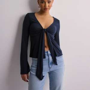 Långärmad ”tie top” -  Mörkblå långärmad topp från Gina Tricot med v-ringning och knyt framtill i storlek XS. Använd ca 1-2 ggr. Går att knyta banden i en rosett eller låta de hänga som på bilden. Säljer då den inte kommer till användning. Inga defekter. 🙌