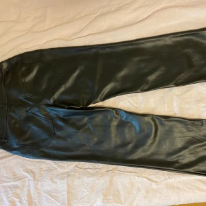 Svarta raka skinnbyxor - Snygga svarta skinnbyxor med raka ben och klassiska fickor både fram och bak. Byxorna har bälteshällor och en stilren look som passar perfekt till en trendig look.