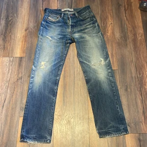 Blå jeans fårn diesel  - Snygga blå jeans från Diesel med slitna detaljer och raka ben. Klassisk femficksmodell med ljusare tvätt och råa kanter nertill. Jeansen har en vintagekänsla och är tillverkade i robust denim. Perfekta för en avslappnad streetstil.