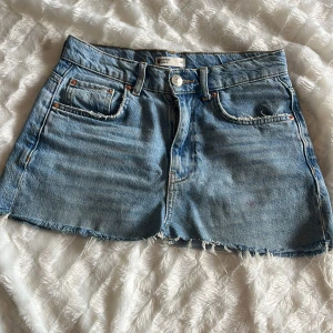 jeanskjol - Snygg blå jeanskjol från Gina Tricot med rå kant nertill och klassiska fem fickor. Modellen är kort och har en avslappnad passform. Perfekt till sneakers eller boots för en cool vardagslook. Storlek 34, pris går att diskutera.  