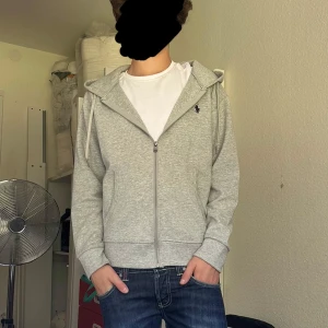Grå Ralph Lauren hoodie. - Perfekta hoodien för våren! Om du letar efter något skönt, snyggt och tidlöst så har du kommit rätt. Modellen i bilden är 15 år, väger 65kg och är 180cm.