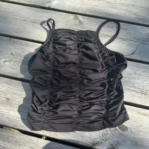 Svart ruched linnetopp med smala band - Säljer en svart topp med smala axelband och snygga rynkade detaljer både fram och bak. Den är från missäy