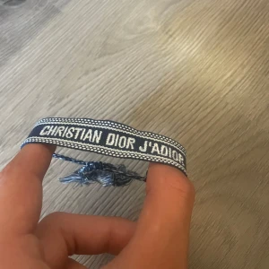  Dior armband  - Snyggt blått armband från Christian Dior med texten 'J'Adior' broderad i vitt. Armbandet har justerbar knytning och tofsar. 