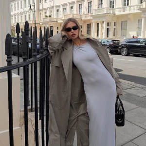 Ljusgrå långklänning i stretch - Supersnygg långklänning i ljusgrått med ärmlös design och rund halsringning. Klänningen har en tight passform som framhäver siluetten och är gjord i ett mjukt, stretchigt material som känns bekvämt hela dagen.