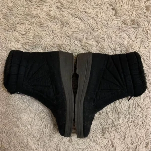 Svarta boots med dragkedja och foder - Mysiga svarta boots med mjukt foder och dragkedja framtill. Skorna har en platt sula och är perfekta för kyligare dagar. Utsidan är i mockaliknande material och insidan är fodrad för extra värme.