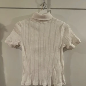 Vit ribbad Zara top - Här är en vit ribbad top med krage kToppen har en hög krage som sitter snyggt på kroppen. Perfekt at styla med jeans eller kjol. Säljer denna för att den inte kommer till användning man betalar även för frakten sen kan man skriva till mig om man har några frågor 