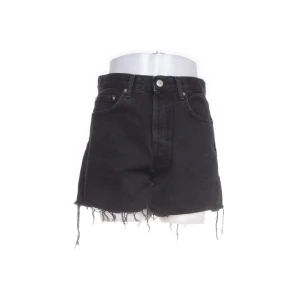 Svarta jeansshorts med fransar från NA-KD - Svarta jeansshorts från NA-KD med hög midja och råa fransade benslut. Klassisk femficksmodell med knapp och dragkedja framtill. 