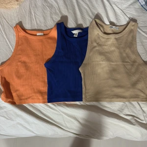 Tre toppar i orange, blå och beige - Säljer tre toppar i färgerna orange, blå och beige. Alla har rund halsringning och är ärmlösa. Perfekta att matcha med jeans eller kjol för en snygg och enkel stil. Den orange och blåa är från H&M och den bege från Zara. En orange och bege är S och den blåa är Xs. Skriv för fler bilder eller ev prisförslag :)