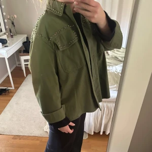 Olivgrön jeansjacka med stenar/pärlor - Säljer en grön jeansjacka från Zara med pärlor/stenar. Använt fåtal gånger går att knäppa ihop armarna.💗