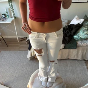 Vita bootcut jeans  - Säljer ett par vita jeans med bootcut-passform och slitningar på benen. Har sytt ut de själv, lite stygn syns, hålen har jag också gjort själv. Finns på vinted.