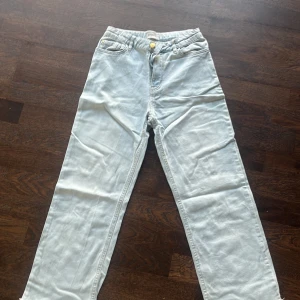 Ljusblå jeansbyxor från Lindex - Säljer ett par ljusblå jeansbyxor från Lindex med klassisk femficksdesign och gylf med dragkedja och knapp. Byxorna har raka ben och bälteshällor i midjan. Perfekta för en avslappnad stil.
