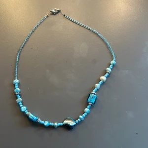 Handgjort blått pärlhalsband - Unikt halsband med små och stora pärlor i olika blå nyanser samt några silvriga detaljer som jag själv har pärlat.