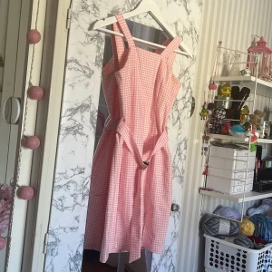 Rutig rosa klänning. - En välfigt fin rosa rutig klänning. Jag säljer den pga att jag rensar min garderob. Jag skulle inte rekommendera den här länningen om du har lång överkropp.Eftersom jag har sytt om den så banden är kortare det finns bild på vad jag har sytt! men man vet alldrig den kanske passar endå. Använt den ungefär max 5 gånger men är endå ett bra skick!