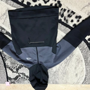 Svart och grå hoodie från The North Face - Säljer en stilren hoodie från The North Face i svart och grått. Jackan har dragkedja framtill, huva och en bröstficka med dragkedja. Perfekt för dig som gillar en sportig och avslappnad look.