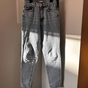Ljusblå jeans från Gina Tricot  - Ljusblå jeans med klassisk femficksdesign och raka ben från Gina Tricot. Jeansen har hög midja, silverfärgad knapp och subtila slitningar. Perfekta för en avslappnad och stilren look.