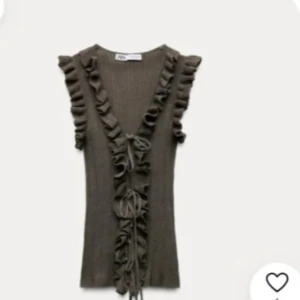 Grön blus från Zara - Säljer en grön ribbad topp från Zara med volangdetaljer längs v-ringningen och axlarna. Toppen har knyt framtill och är ärmlös, perfekt för lager-på-lager eller som statement-plagg. Har några lösa summar men annars inget jag tänkt på när jag har använt den 