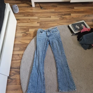 Blå bootcut jeans från Denim Rebel - Säljer ett par blå bootcut jeans från Denim Rebel med snygga fickor bak som har nitar och knappdetalj. Jeansen har normal passform och klassisk denimlook. Perfekta för dig som gillar en tidlös stil med lite extra detaljer.